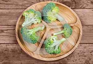 Branches of fresh raw broccoli on the wooden serving dish