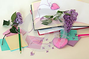 Branches of lilac flowers on the table, paper, notebooks, pencils