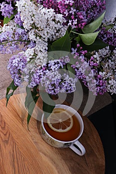 Branches of lilac and white lilac in a wicker basket and a cup of black tea with lilac flowers isolated on a white background