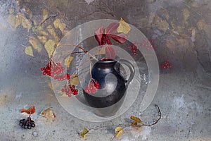 Branches with red berries in a vase.Autumn still life berries fireplaces, yellow leaves in a vase on a brown background