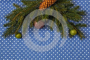 Branches of spruce with Christmas balls and cone on a background of cloth in polka dots