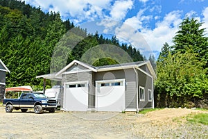 Brand detached double garage with car and boat parked on gravel driveway