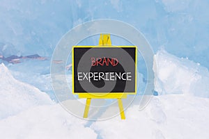 Brand experience symbol. Concept words Brand experience on beautiful yellow black blackboard. Beautiful blue ice background.