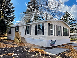 Brand new prefab mobile home with for sale yard sign post, colorful fall foliage near Rochester, New York