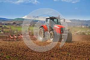 Brand new red tractor plowing the land