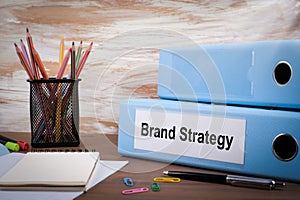 Brand Strategy, Office Binder on Wooden Desk. On the table colored pencils, pen, notebook paper