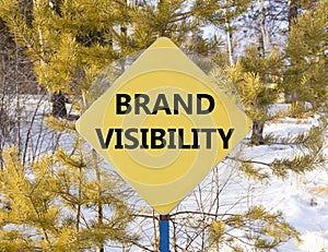 Brand visibility symbol. Concept words Brand visibility on beautiful yellow road sign. Beautiful forest snow blue sky background.