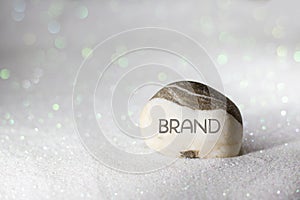 BRAND word carved on stone on white sand with glittering
