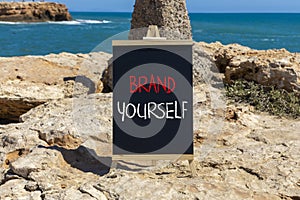 Brand yourself symbol. Concept words Brand yourself on beautiful black blackboard. Beautiful sea stone sky background. Business