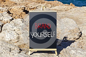 Brand yourself symbol. Concept words Brand yourself on beautiful black blackboard. Beautiful sea stone sky background. Business