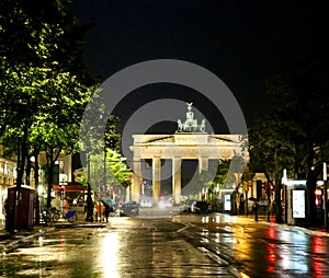 Brandenburg Gate at night with reflections of lights on asphalt photo