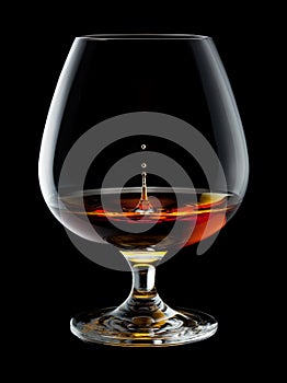 Brandy Glass with drops and splash on black photo