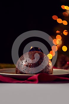 Brandy Soaked Christmas Pudding With Flames On Table Set For Festive Christmas Meal