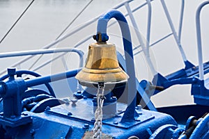Brass bell on the foredeck of a ship in cloudy light