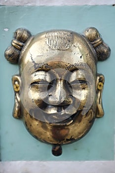 Brass / bronze chinese mask on green cement wall