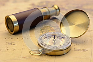 Brass compass and old telescope on vintage map world explorer concept