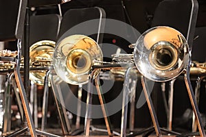 Brass French horn bells on black and silver metal stage concert chairs