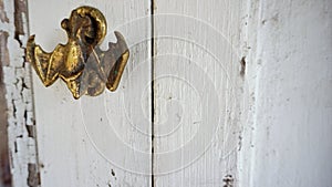 Brass hanging bat door knocker welcomes to rustic doorway