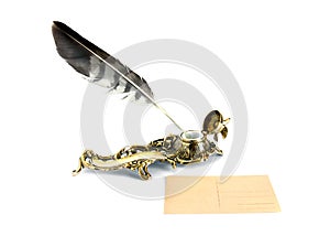 Brass inkwell with feather and postcard