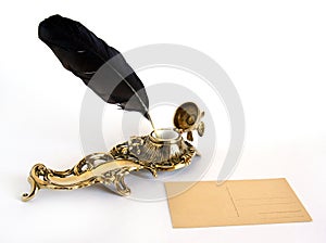 Brass inkwell with feather and postcard