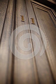 Brass number 11 on a wooden panelled door, with a shallow depth of field