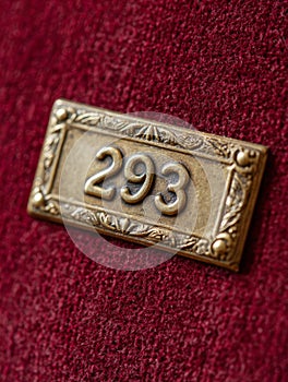 Brass number '293' plaque on a red velvet background.