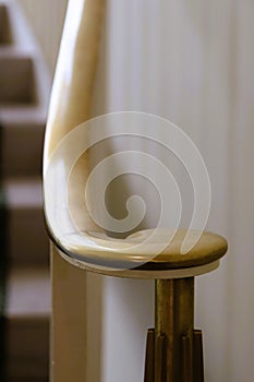 Brass railing and volute newel at bottom of staircase against white, vertical