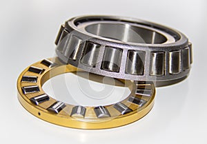 Brass roller cage of a thrust roller bearing and stainless roller cage of a tapered roller bearing