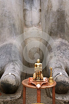 Brass statue infront of a gigiantic monolithic statue of Bahubali, photo