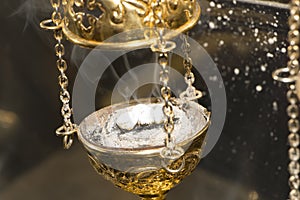 Brass thurible liturgy censer with burning incense in it