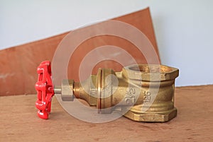 Brass valve with red knob in a factory plumber on wooden floor background