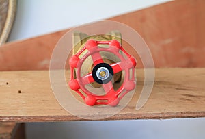 Brass valve with red knob in a factory plumber on wooden floor background