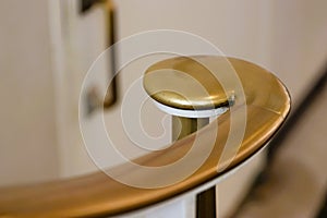 Brass volute newel at bottom of staircase against white photo