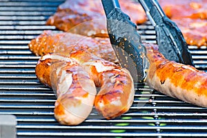 Brat sausage is served on the charcoal grill with the grill tongs photo