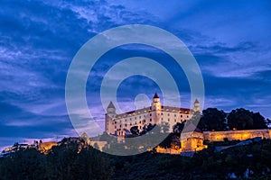 Bratislava castle illuminated in evening glow against dramatic sky