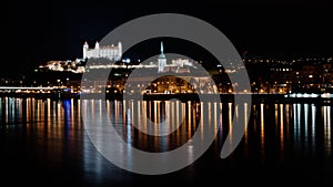 Temná nočná panoráma Bratislavy s odrazmi v rieke Dunaj