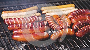 Brats being cooked on a grill with flame and smoke