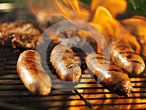 Bratwursts cooking on flaming grill