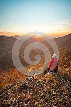 Odvážny dobrodruh sedí na skale pri západe slnka v oblasti Mojtín v Strážovských vrchoch na Slovensku. Meditácia na vrchole