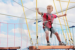 Brave blond hair kid playing rope course outdoor