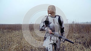A brave blonde in armor goes to the field and clings to the sword
