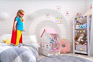 Brave cute little girl wants to jump out of bed, imagining flight