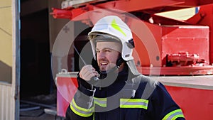 Brave firefighter man talking to walkie talkie with fire truck in background