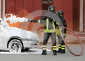 brave firefighters with foaming fire off the car fire after the