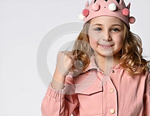 brave girl in a plush crown, close-up portrait, shows her fist or hand but at the same time smiles at the camera.