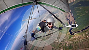 Brave hang glider pilot soar high over town and river.