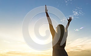 Brave happy young woman raising hands up in the air.