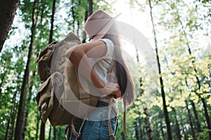 Hipster girl traveling alone and looking around in forest on outdoors wearing treveler backpack and hold location map in han