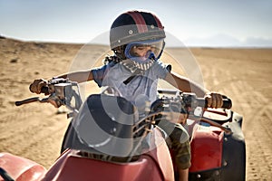 Kid in helmet and protect mask riding quad bike