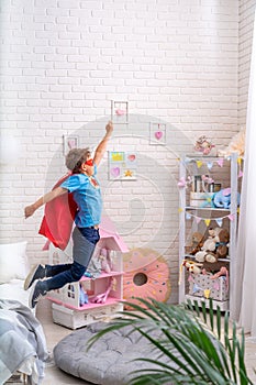 Brave little boy jumps out of bed, imagining flight. child plays superhero